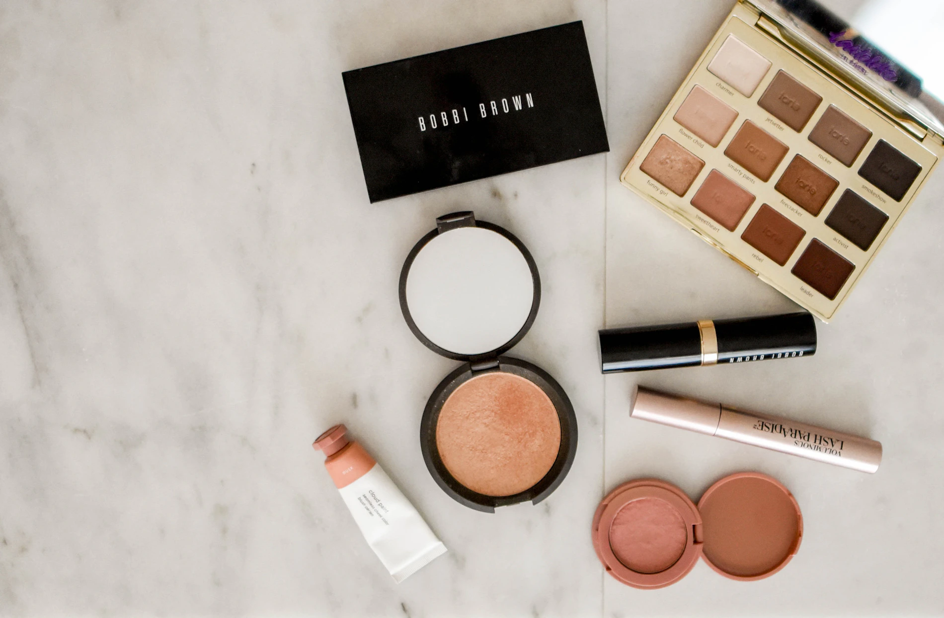 Composição de frascos e produtos de beleza sobre superfície escura, com reflexos dourados